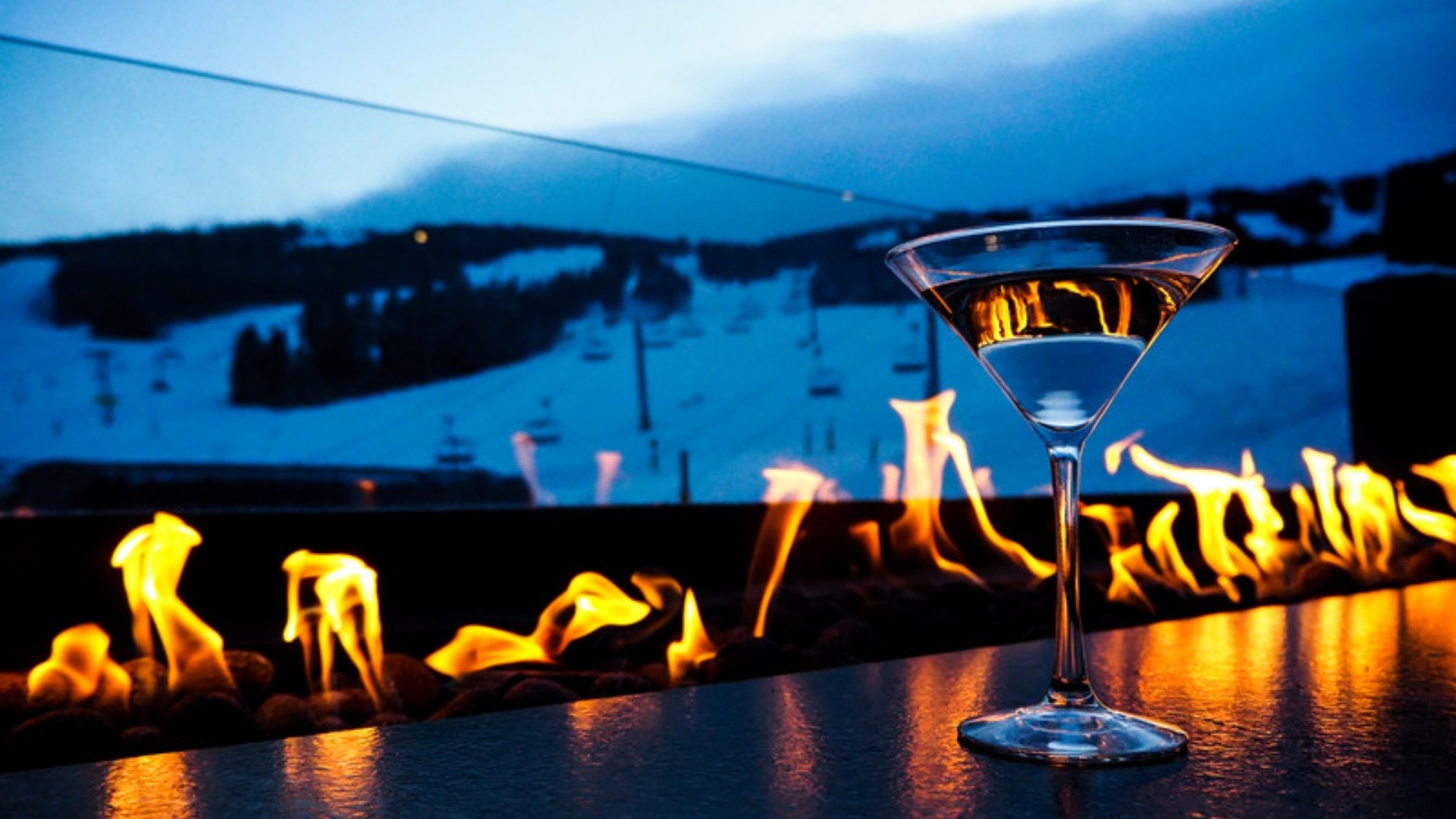 Après-ski fire pit and cocktail facing the slopes at dusk