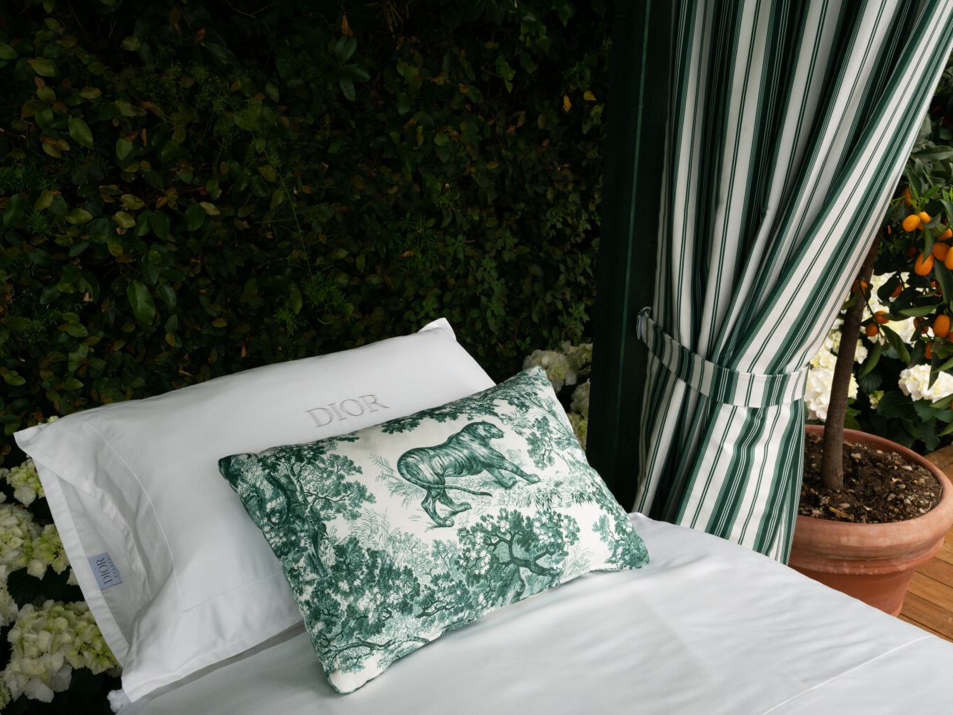 A daybed with a Dior Toile de Jouy cushion beneath a striped cabana curtain at the Dior Spa Splendido, Portofino