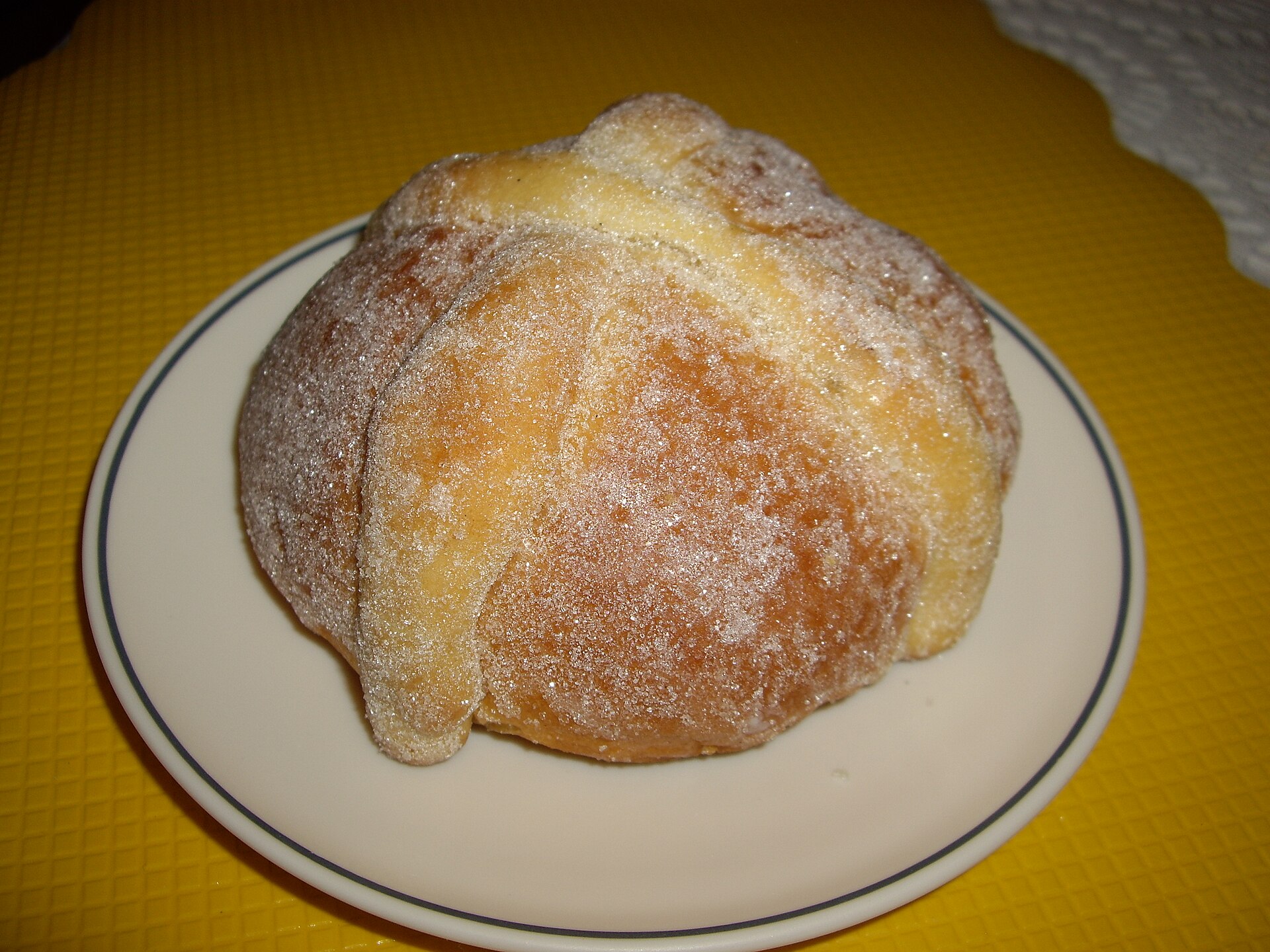 A round loaf of pan de muerto dusted with sugar
