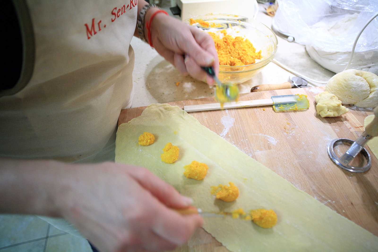Hands filling fresh pasta with pumpkin filling to make tortelli di zucca